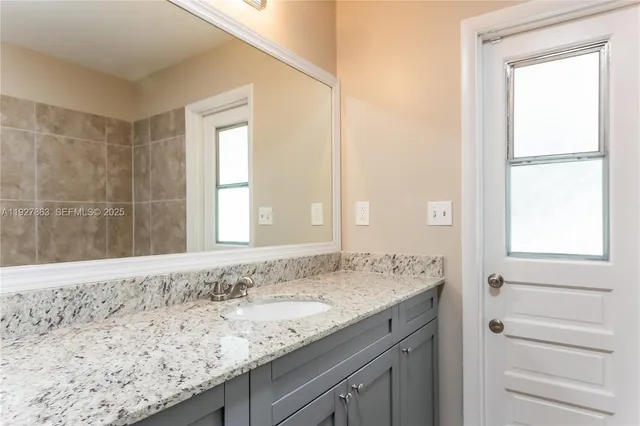 a bathroom with a granite countertop sink and a mirror