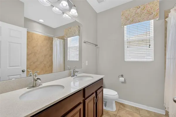 a bathroom with a granite countertop sink a toilet and a mirror