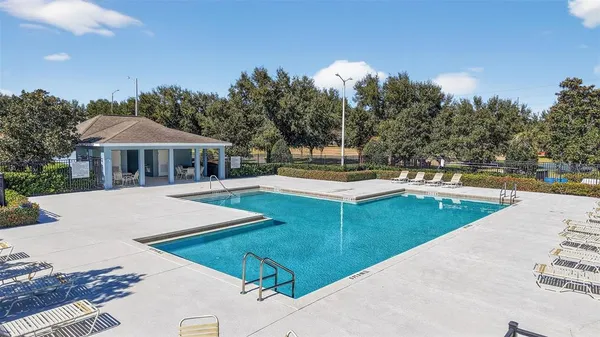 a view of a house with pool and trees in the background