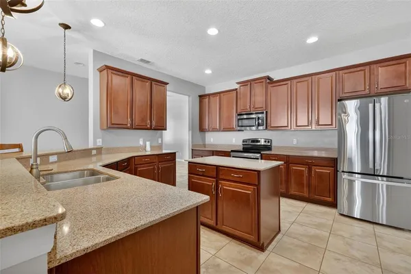 a kitchen with stainless steel appliances granite countertop a sink a stove and a refrigerator