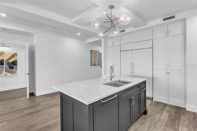 a kitchen with a sink chandelier and wooden floor