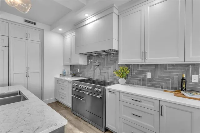 a kitchen with stainless steel appliances granite countertop a sink a stove and a white cabinets