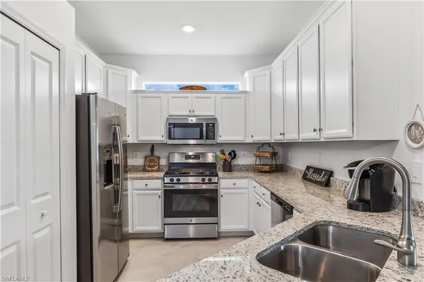 a kitchen with stainless steel appliances a sink a stove a refrigerator cabinets and a counter top space