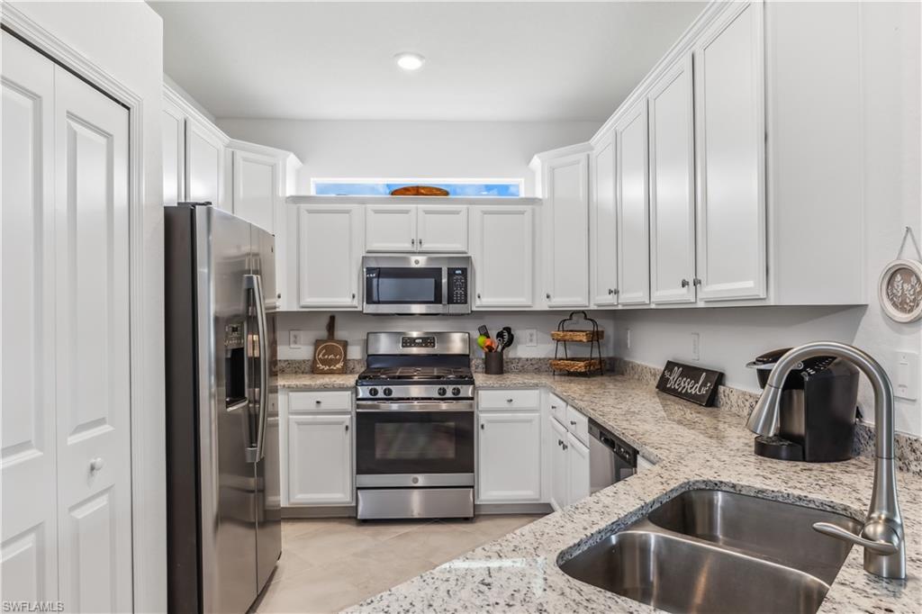 17716 Palmetto Pass Lane Babcock Ranch, FL 33982 - Photo 9 of 20 a kitchen with stainless steel appliances a sink a stove a refrigerator cabinets and a counter top space