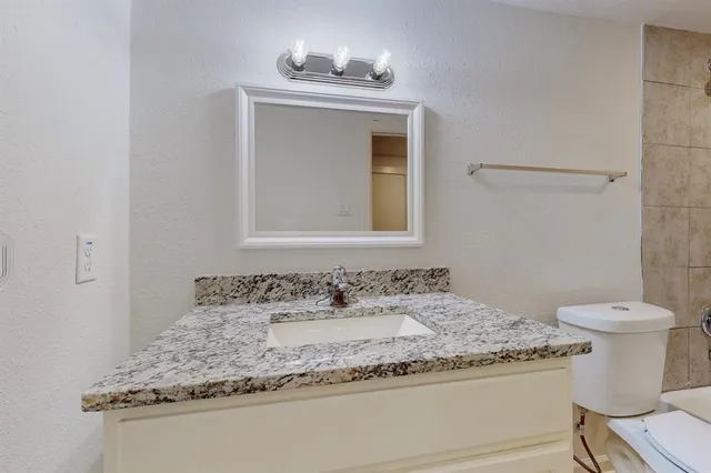 a bathroom with a granite countertop sink a toilet and bathtub