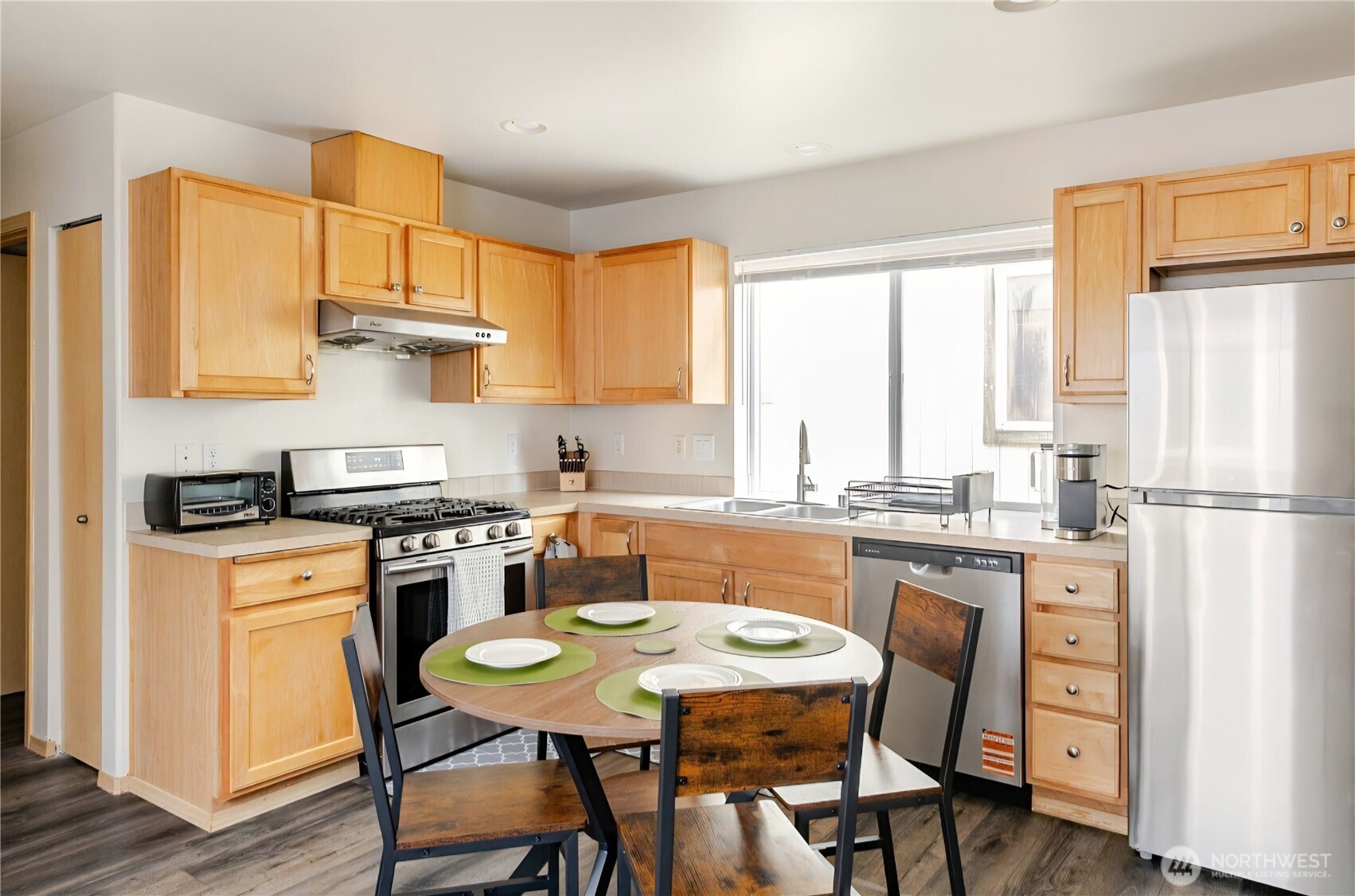 10047 17th Avenue Southwest Seattle, WA 98146 - Photo 9 of 27 a kitchen with stainless steel appliances granite countertop a stove a refrigerator a dining table and chairs