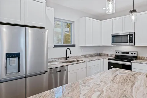 a kitchen with stainless steel appliances granite countertop a refrigerator sink and microwave