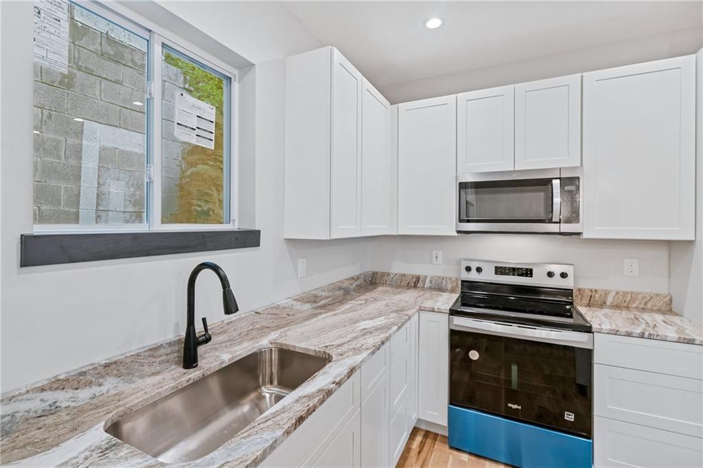 1102 Spring Garden Avenue Pittsburgh, PA 15212 - Photo 10 of 25 a kitchen with granite countertop a sink and a stove top oven with wooden floor