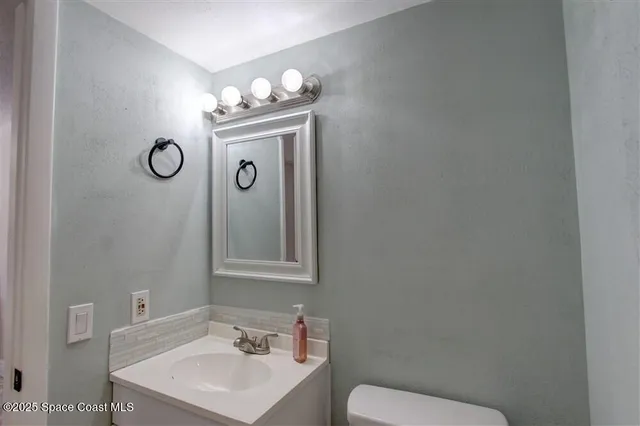 a bathroom with a toilet sink vanity and mirror