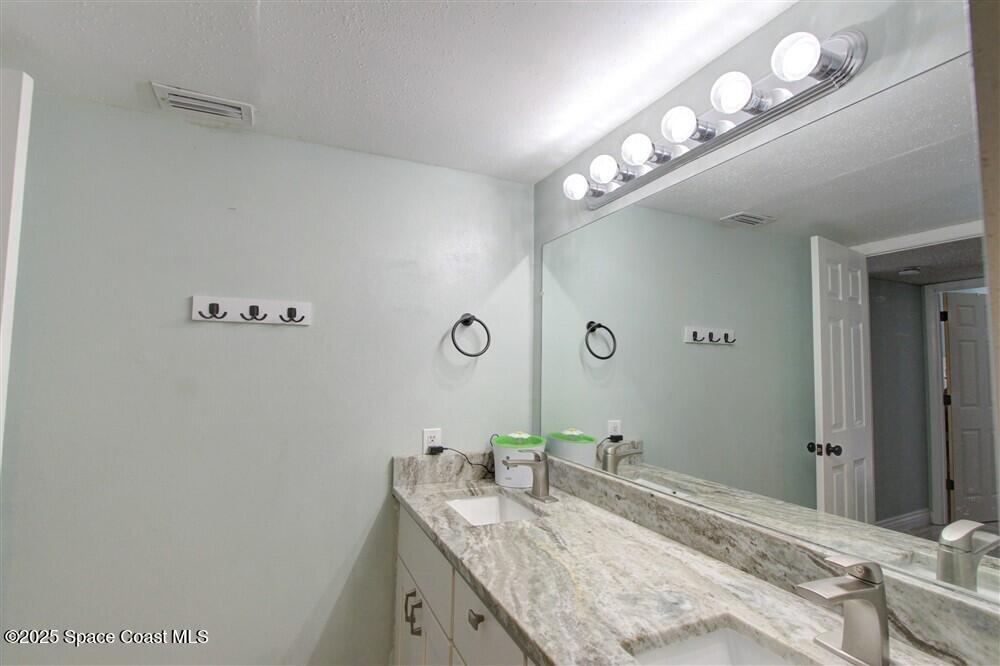 1717 Patty Circle Northeast Palm Bay, FL 32905 - Photo 25 of 35 a bathroom with a granite countertop sink a light fixture and a mirror