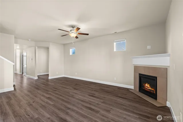 a view of an empty room with wooden floor fireplace and a window