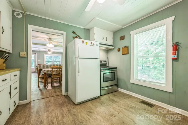 a view of a kitchen with refrigerator and wooden floor
