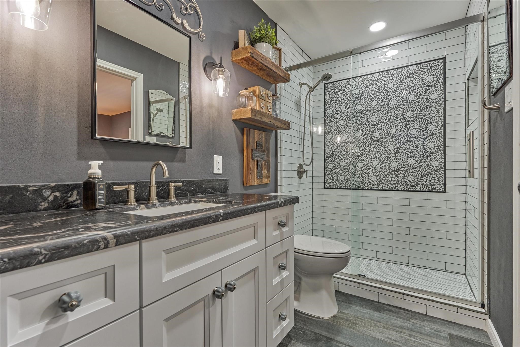 1 April Point Drive South Montgomery, TX 77356 - Photo 23 of 45 The bathroom was taken down to the studs to add insulation, a seamless glass shower, and designer tile. The vanity area features custom lighting, a granite countertop and soft close cabinets and drawers. Behind the mirror reveals a medicine cabinet for extra storage.