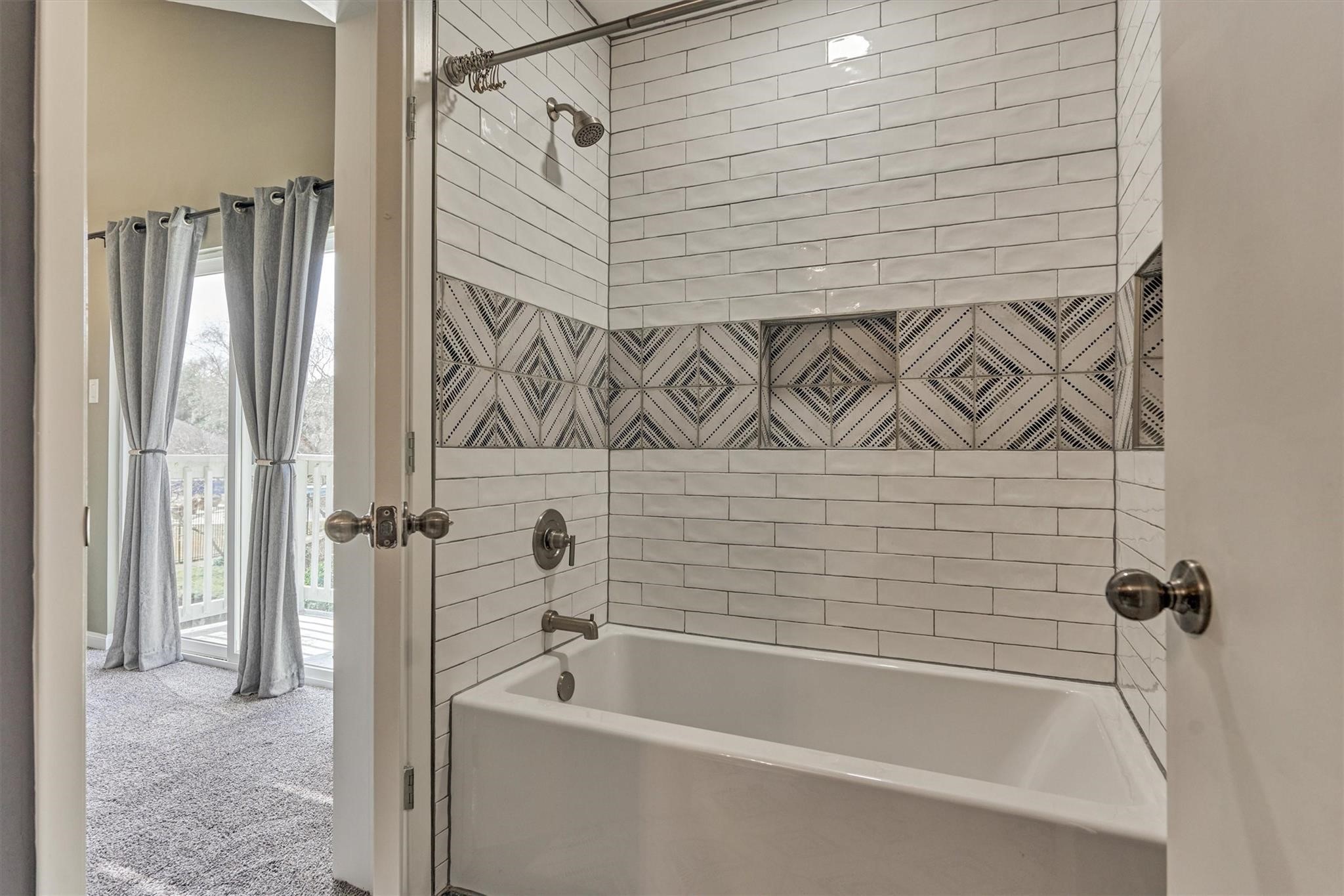 1 April Point Drive South Montgomery, TX 77356 - Photo 28 of 45 A tub/shower in the second floor bath has a striking custom tile design and features niches for bath products.