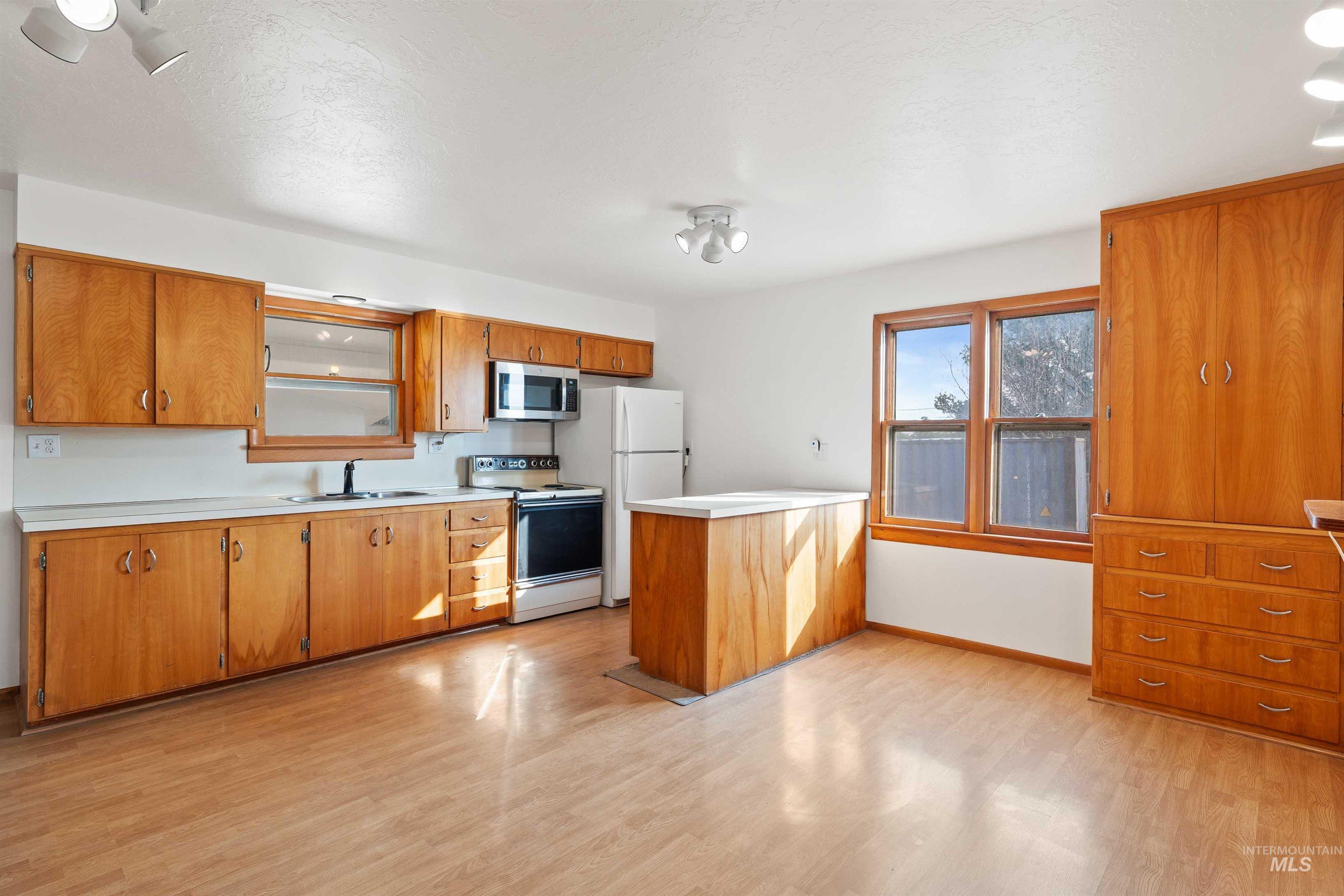 321 Clear Lakes Road Buhl, ID 83316 - Photo 6 of 34 Kitchen featuring wood-finish flooring, wood cabinetry with minimalist hardware, a central island, and white appliances