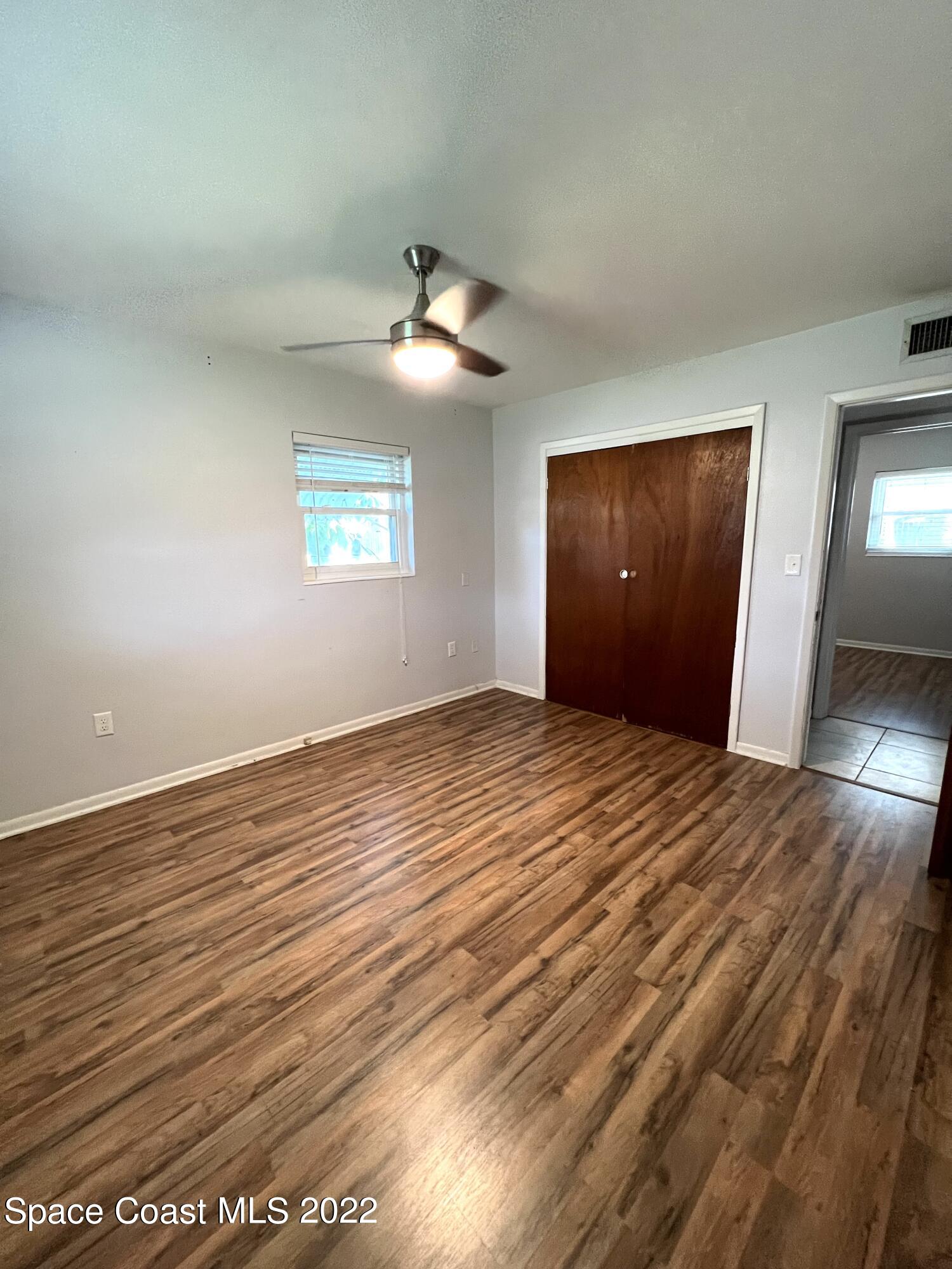 282 Fay Drive Indialantic, FL 32903 - Photo 18 of 27 an empty room with wooden floor chandelier fan and windows