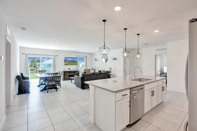 a kitchen with stainless steel appliances granite countertop a sink a counter top space and living room view