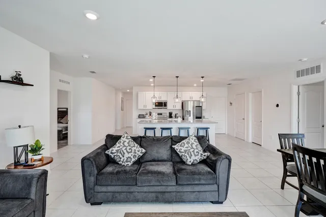 a living room with furniture white walls and kitchen view