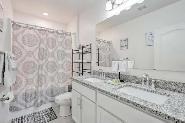 a bathroom with a granite countertop sink a toilet and a mirror