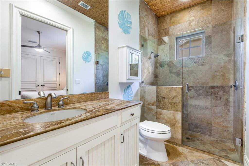 516 Portside Drive Naples, FL 34103 - Photo 14 of 33 a bathroom with a granite countertop sink toilet a mirror and shower