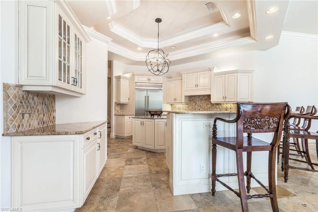 516 Portside Drive Naples, FL 34103 - Photo 21 of 33 a kitchen with stainless steel appliances granite countertop a stove top oven a refrigerator a sink and a dining table with chairs