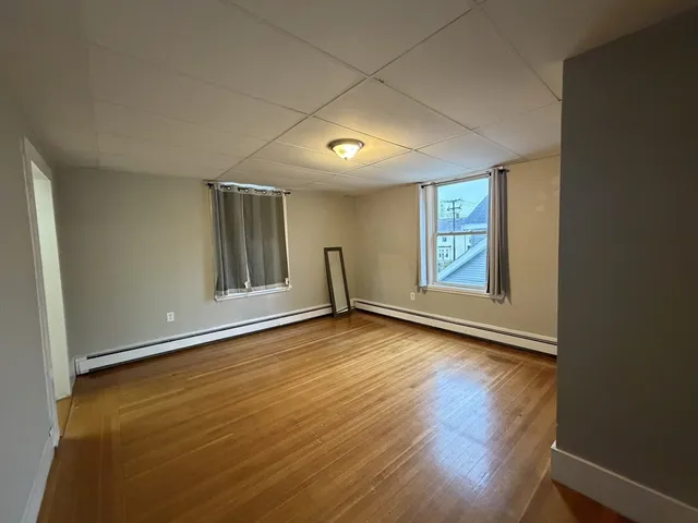 a view of an empty room with a window and wooden floor