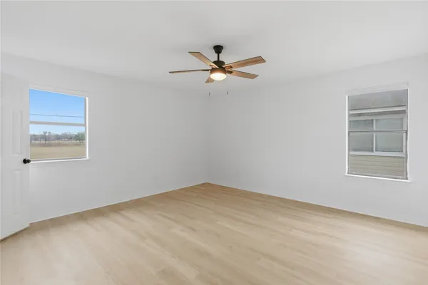an empty room with windows and fan