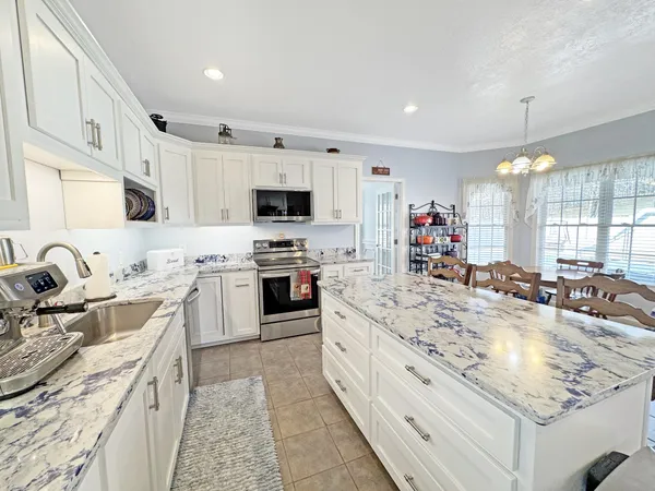 a large white kitchen with stainless steel appliances granite countertop a stove oven and a white cabinets