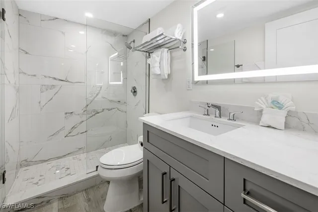 a bathroom with a sink toilet vanity and shower