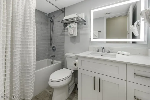 a bathroom with a toilet sink vanity tub and mirror