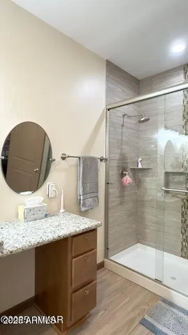 a bathroom with a granite countertop sink a mirror and shower