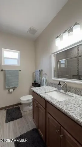 a bathroom with a granite countertop sink a toilet and a mirror
