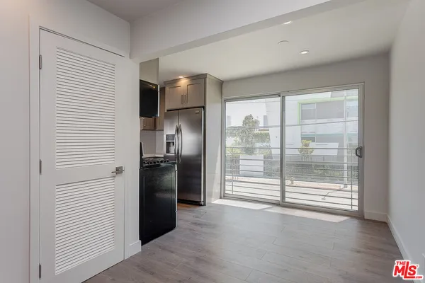 a view of a kitchen with refrigerator and wooden floor