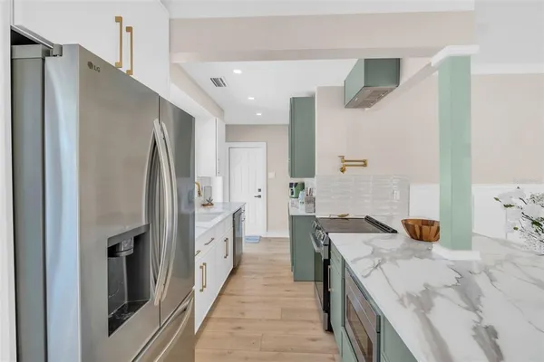 a large kitchen with stainless steel appliances granite countertop a refrigerator and a sink