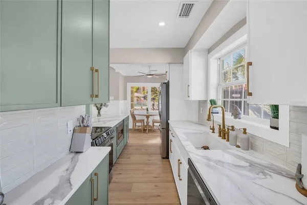 a large white kitchen with a large window and stainless steel appliances