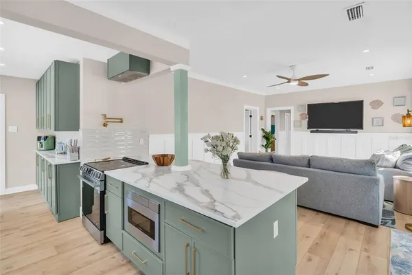 a living room with stainless steel appliances granite countertop a kitchen island a stove and a sink