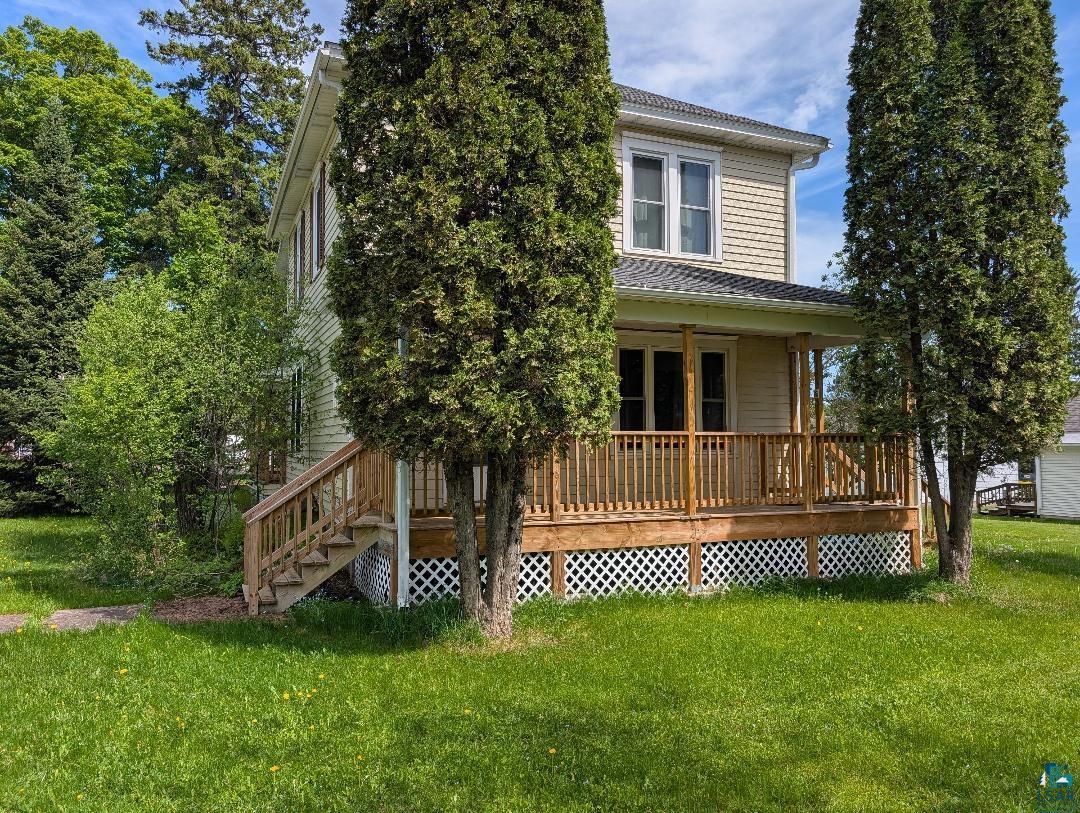 202 Thomas Street Mellen, WI 54546 - Photo 3 of 6 Two-story residence with light-toned siding and a covered front porch featuring a natural wood railing