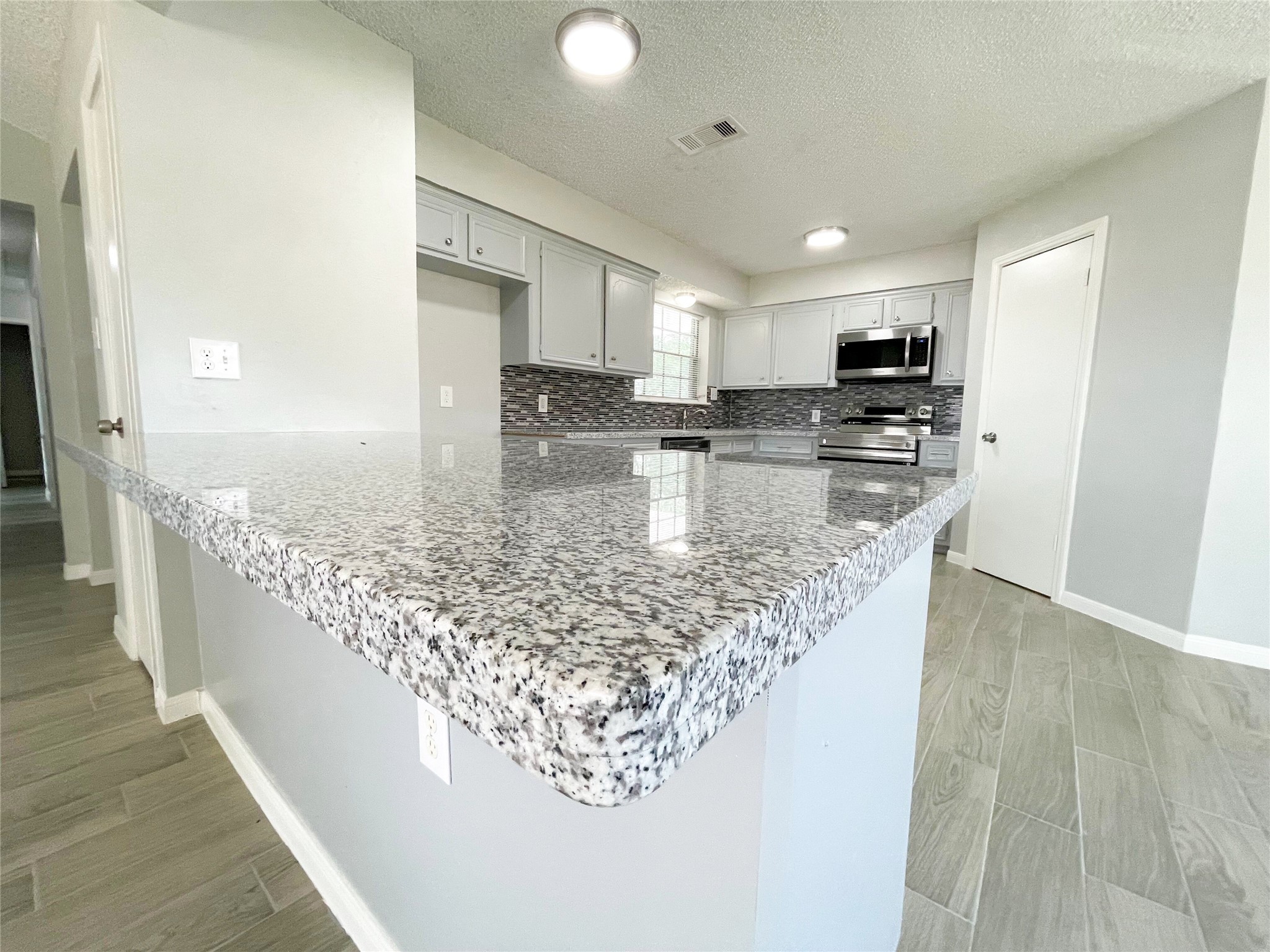 23460 Smith Road Porter, TX 77365 - Photo 16 of 46 a kitchen with kitchen island granite countertop a sink stove and cabinets