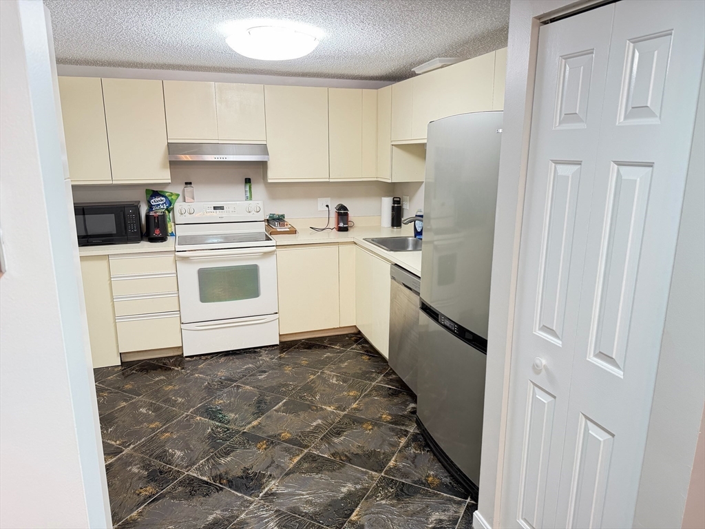 8 9th Street, Unit 511 Medford, MA 02155 - Photo 10 of 12 a kitchen with a white cabinets and white appliances