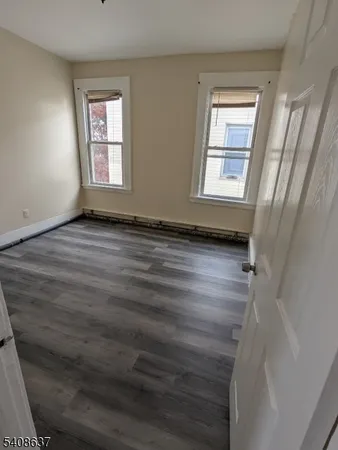 a view of an empty room with wooden floor and window