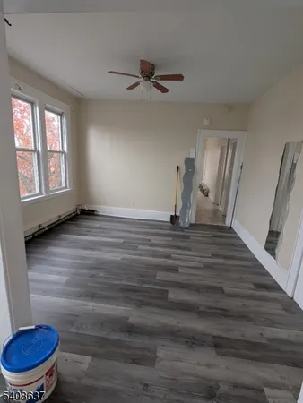 a view of an empty room with a window and wooden floor
