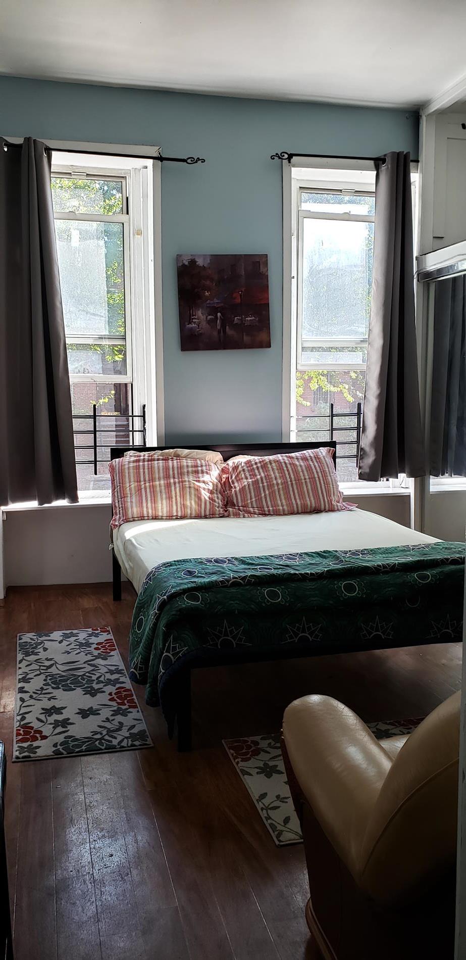a bedroom with a bed couch and a large window