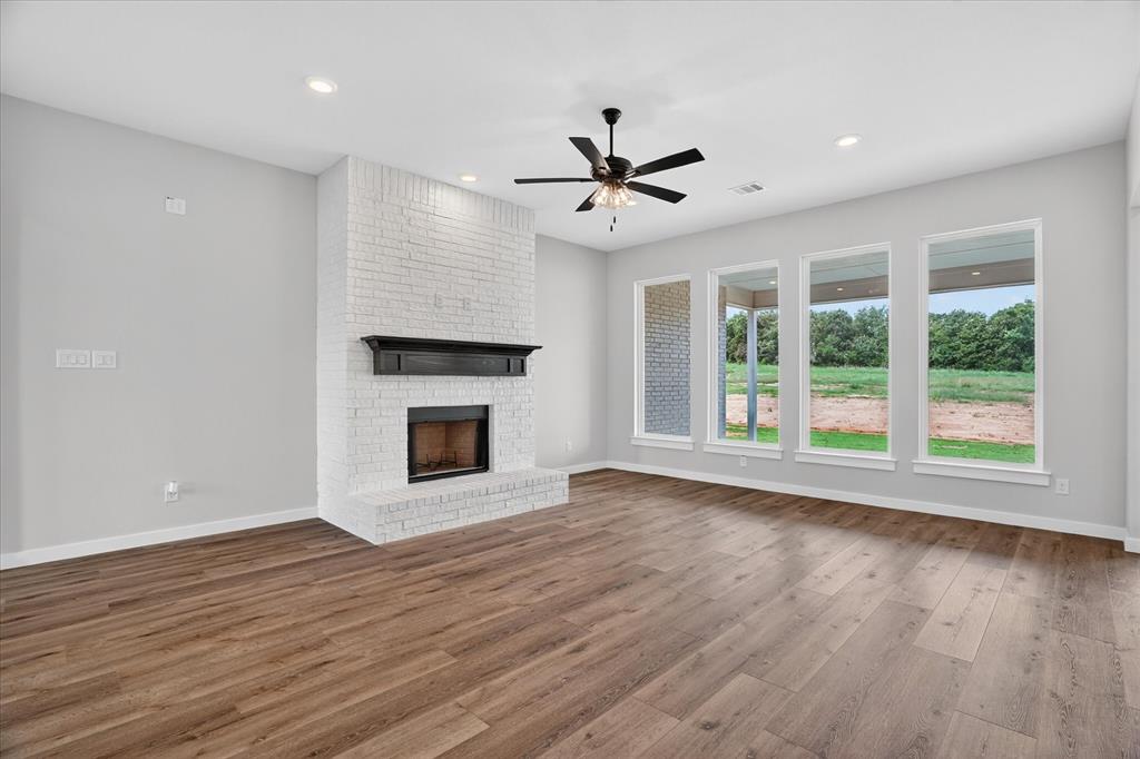 317 Skeen Peak Springtown, TX 76082 - Photo 10 of 31 Spacious room featuring a white brick fireplace with a dark wood mantel, wood-finish flooring, recessed lighting, and a ceiling fan