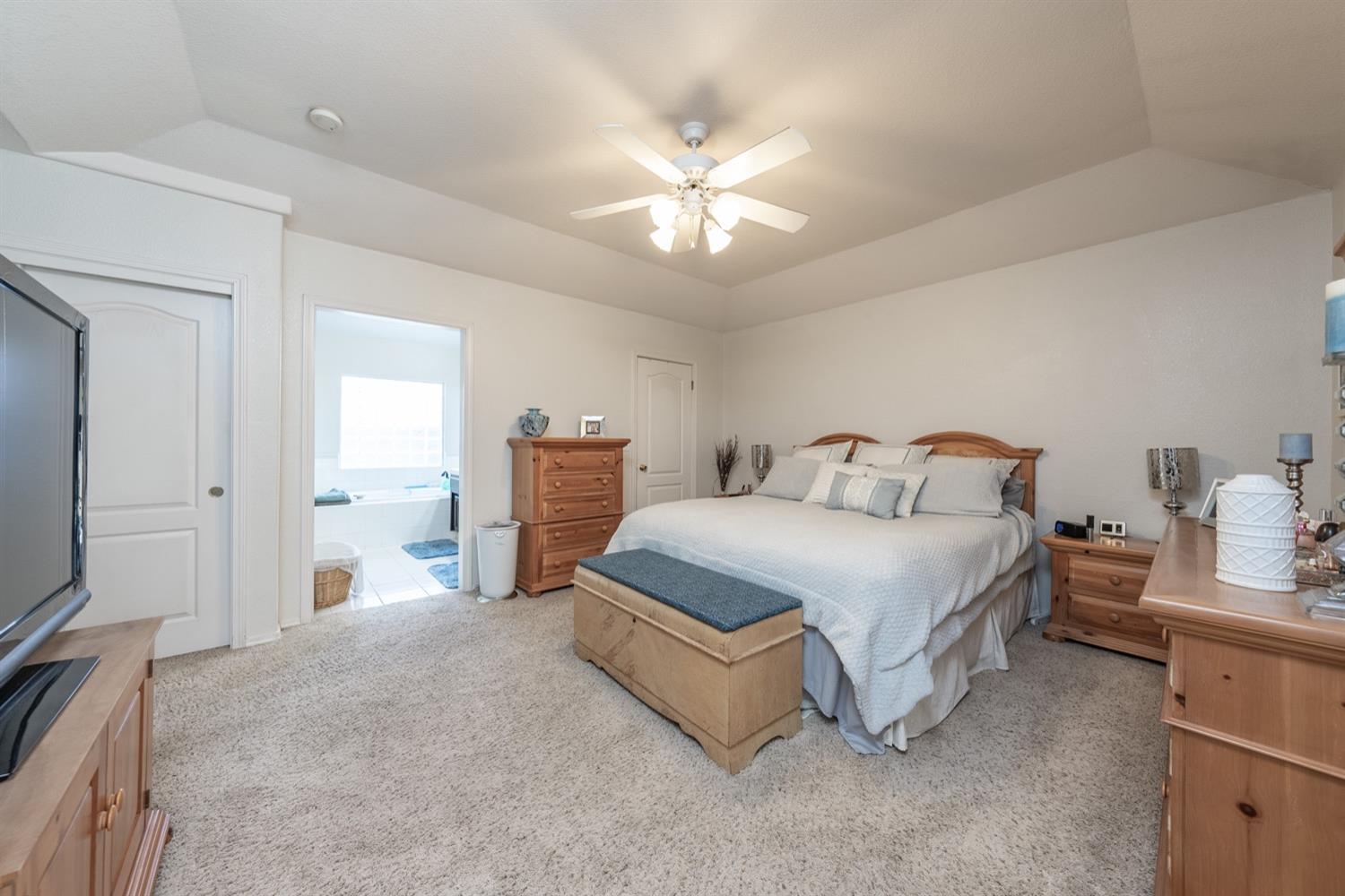 3432 Doubletree Way Madera, CA 93637 - Photo 18 of 45 a spacious bedroom with a bed and a flat tv screen on dresser