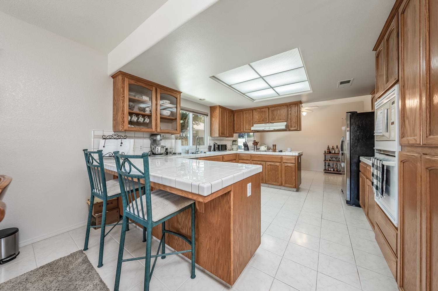 3432 Doubletree Way Madera, CA 93637 - Photo 8 of 45 a kitchen with stainless steel appliances kitchen island granite countertop a table chairs in it and a window