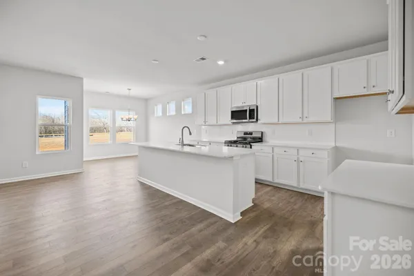 a kitchen with stainless steel appliances granite countertop a white cabinets a sink a stove a dining table and chairs