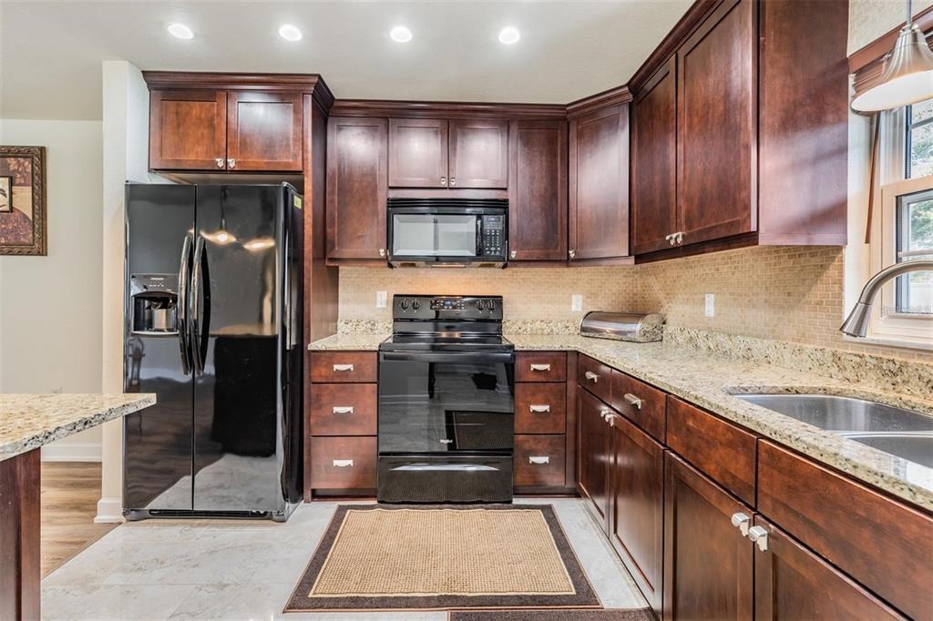 701 Poinsettia Road, Unit 248 Belleair, FL 33756 - Photo 11 of 38 a kitchen with granite countertop stainless steel appliances and wooden cabinets counter space