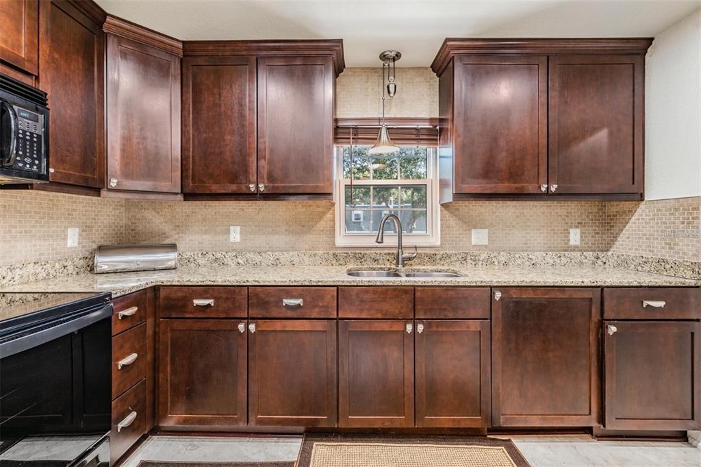 701 Poinsettia Road, Unit 248 Belleair, FL 33756 - Photo 12 of 38 a kitchen with granite countertop a sink cabinets and wooden floor