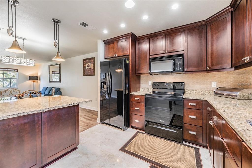 701 Poinsettia Road, Unit 248 Belleair, FL 33756 - Photo 13 of 38 a kitchen with stainless steel appliances kitchen island granite countertop a refrigerator stove and oven