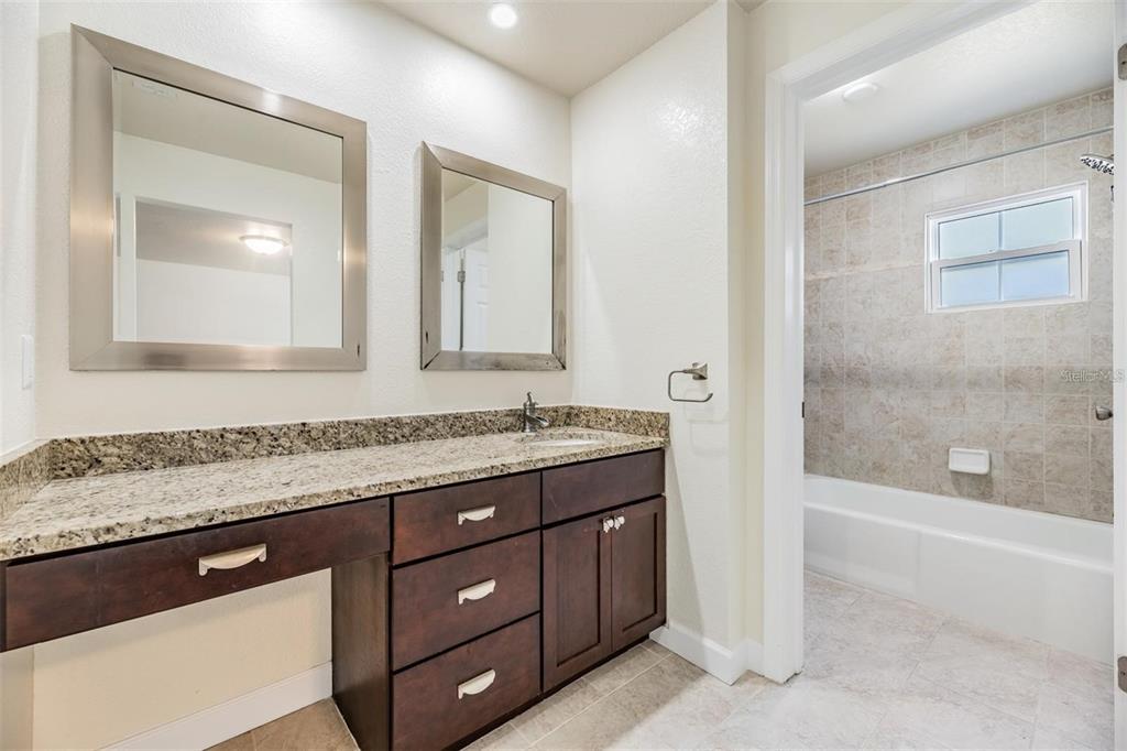 701 Poinsettia Road, Unit 248 Belleair, FL 33756 - Photo 18 of 38 a bathroom with a granite countertop sink a mirror and a bathtub
